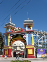 The colourful entrance to an amusement park, through the gaping mouth of a slightly sinister looking man in the moon.