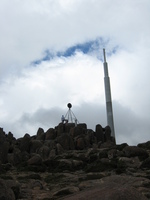 The peak of a mountain, a large communications mast rises behind it.