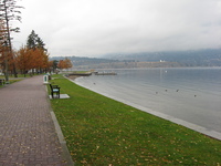 On the left a path stretches off, dotted with benches.  On the right a view across a lake to mountains on the far side.
