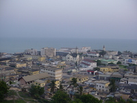 Multi-coloured buildings with a few church spires, the sea in the background.