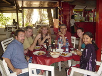 A group of people sitting around a table with food and drinks