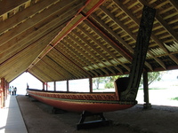 A large wooden canoe sits under a roof.