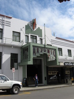 An Art Deco hotel frontage, cars parked in front.