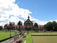 A large Victorian Gothic building stands behind bowling greens.