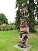 A colourful carved totem pole stands on a lawn.
