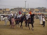 Young boys in their costumes riding horses around the arena