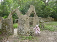 Eleanor squatting beside a sculpture at the entrance to the Osun shrine