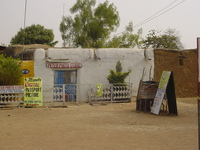 A traditional Hausa house, painted white with a sign saying 'Peter's Photo Studio'