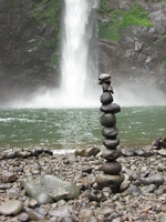 Stones piled on top of each other in front of a waterfall.