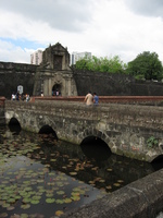 A stone gateway seen over a lily-pad covered moat.