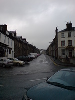 A steeply sloping street, wet after recent rain.