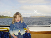 Eve standing in front of a window on a ferry, through the window can be seen the Firth of Clyde and the hills near Helensburgh