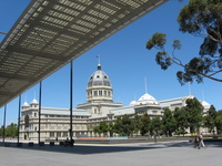 Seen beyond a modern roof shading a pathway is a domed exhibition building.