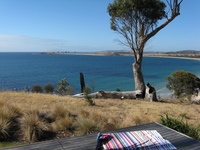 View from a wooden deck overlooking a bay with clear blue water.