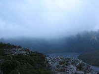 Mountains rising behind a lake are hidden by cloud.