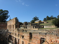 View from inside a ruined stone building over well-kept lawns and other buildings in various states of repair.