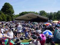 Picture of the main stage at the folk festival, with lots of people sitting out on the grass in front of it