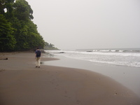 Charles walking along a beach of chocolate-coloured sand