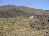 Small hut (with a few people outside) in front of a peak