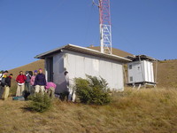 Crowd of people outside a ramshackle hut