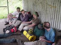 Part of the group sitting against the outside of a corrugated metal hut