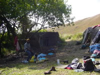 Peter the guide with equipments, traditional huts in background