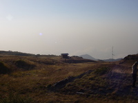 View down grassy slope to small hut