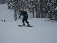Me snowboarding uncertainly. A beginner (me) snowboarding badly, snow falling between the camera and subject.