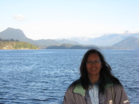 Mo standing in front of a body of water, mountains in the background.