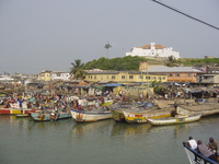 A whitewashed fort sits on a hill above a fishing harbour.