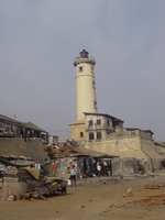 An old stone lighthouse pokes out of a slum