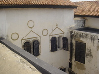 Arched windows in a white building with the remains of decorative stonework around them.