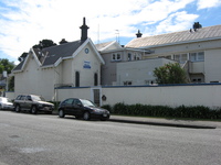 A rambling white painted house on a residential street.