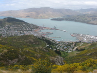 View down onto a small town nestled between hills and a clear blue bay.