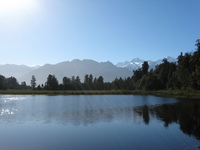 A lake with small ripples just about reflects mountains seen in the background.