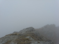 A bit of rock can be seen among low cloud, fog and rain.