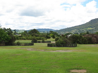 An open lawn in a park, small wooden fences surround parts of the park.