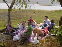Group of people having a picnic on a rock by a reservoir