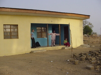 Small yellow house, three people standing on the verandah