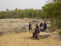 A group of small Nigerian boys sitting on rocks by the side of the river