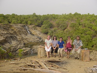 Five people sitting on a flimsy wooden bench in front of the main fall