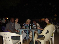 A group of people sitting around a plastic table with beers