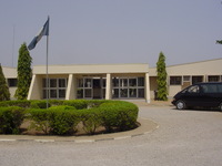 A single-storey white building with the Nigerian flag flying outside