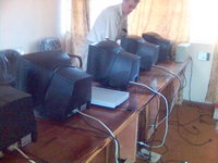 A small room with two large desks and five computers.  Kevin is standing behind one of the computers.