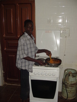 Suleiman standying by a cooker, stirring the contents of a large frying pan.