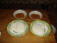 Two plates each with two balls of tuwo and two bowls of red stew.