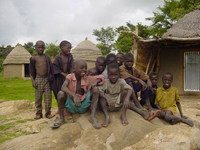 Scruffily-dressed small boys sitting on a rock