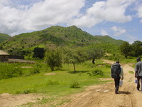 A dirt track in the foreground leads up a green hill