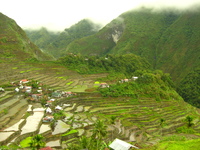 Small houses with thatch or metal roofs among rice terraces in the mountains.