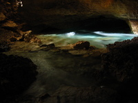 A cave with bright blue water flowing through it.